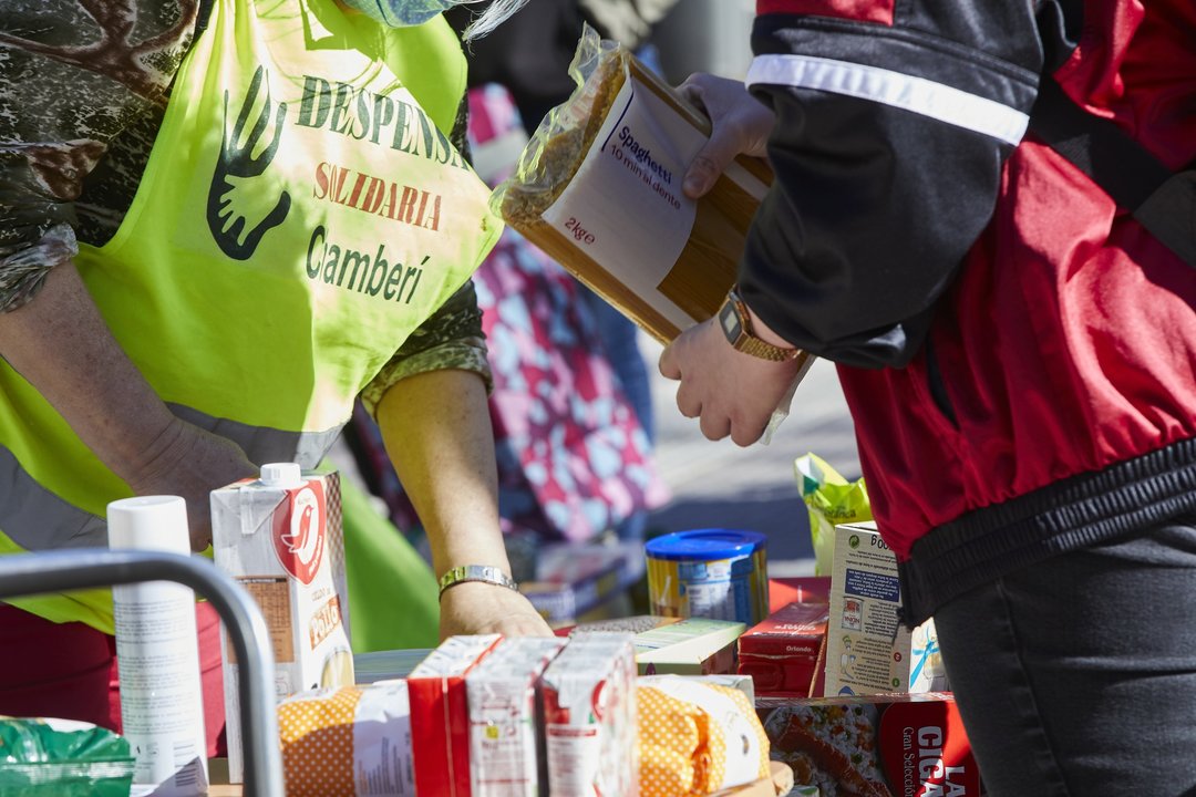 Varios miembros de la Despensa Solidaria de Chamberí reparte alimentos a familias vulnerables en la Plaza de Chamberí frente a las puertas de la Junta de Distrito, en Madrid (España), a 13 de marzo de 2021