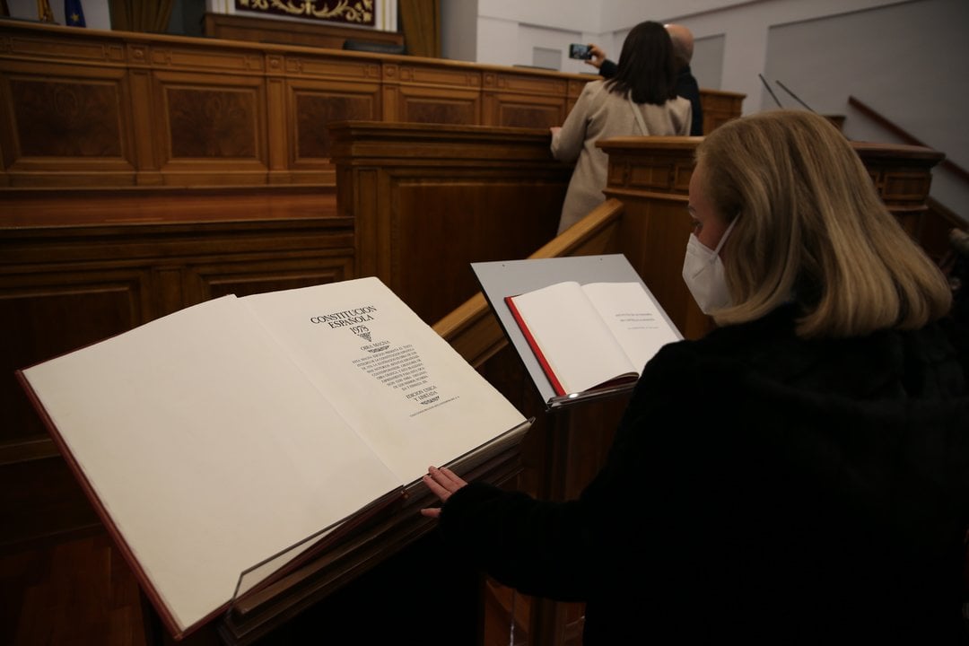 Una mujer observa un ejemplar de la Constitución Española, en el salón de plenos de las Cortes de Castilla-La Mancha, a 4 de diciembre de 2021, en Toledo, Castilla-La Mancha (España).