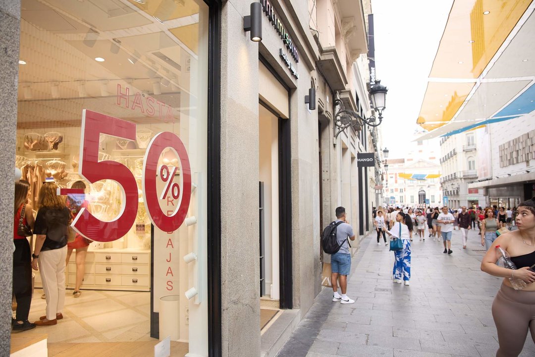 Varias personas caminan con bolsas durante el comienzo de las rebajas de verano, en el centro de Madrid