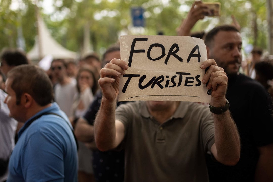 Una persona sujeta un cartel durante una manifestación contra el turismo masificado, a 6 de julio de 2024, en Barcelona. (Foto: Lorena Sopêna / Europa Press)